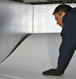 A contractor installing TerraBlock™ floor insulation in a Absecon crawl space