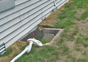 The ugly, old concrete window well of a Clementon crawl space