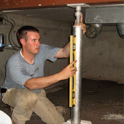 A contractor in Millville installing a crawl space jack post.