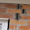 A brick wall displaying stair-step cracks and messy tuckpointing on a Bridgeton home