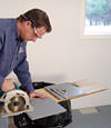 installing a waterproof vapor barrier on a basement floor to prepare for basement carpeting in a Bridgeton home